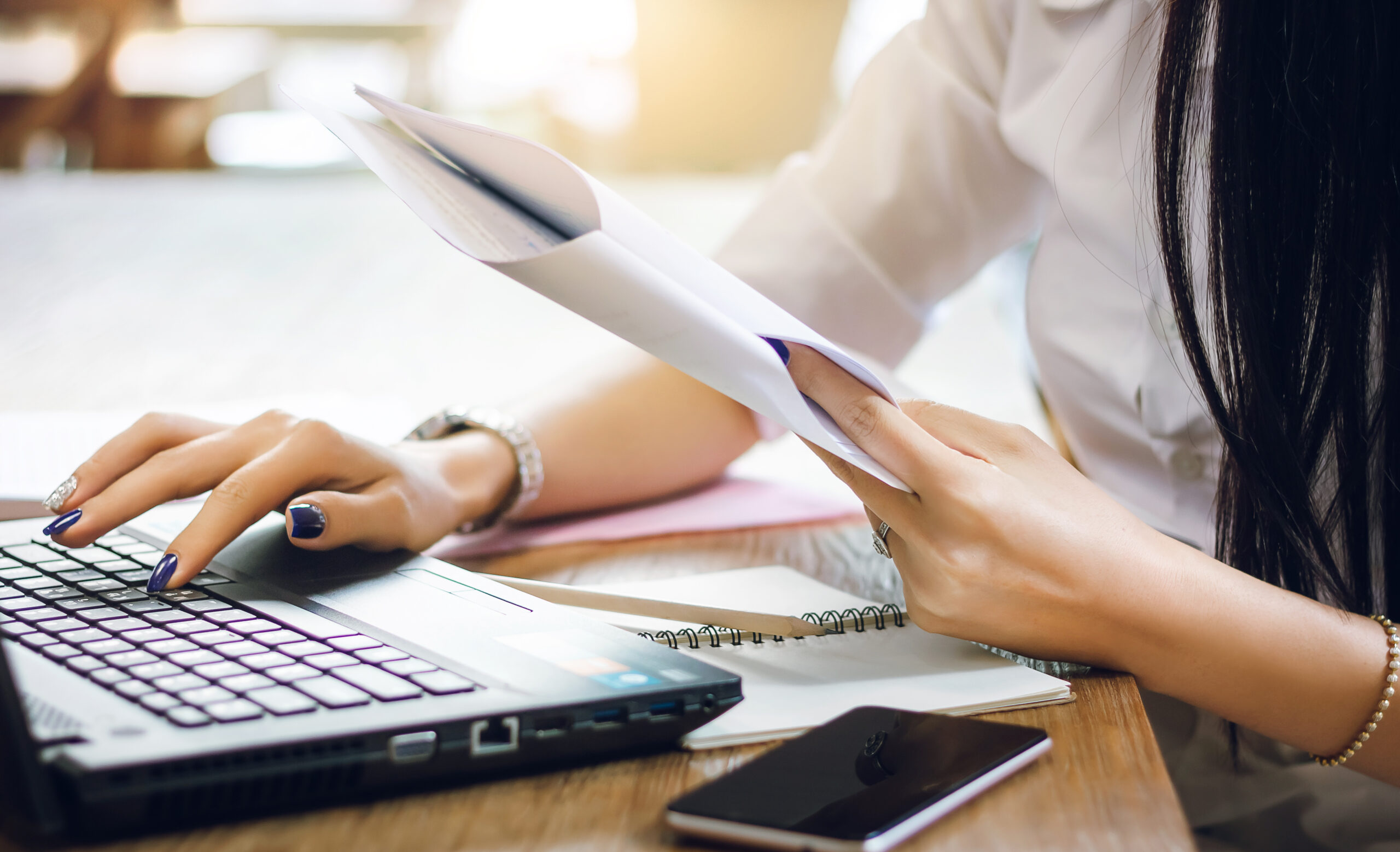 Closeup. businesswoman reading on paperwork and using laptop working on desk