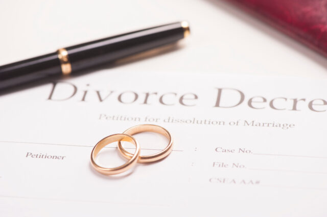 divorce decree with wedding bands and a pen