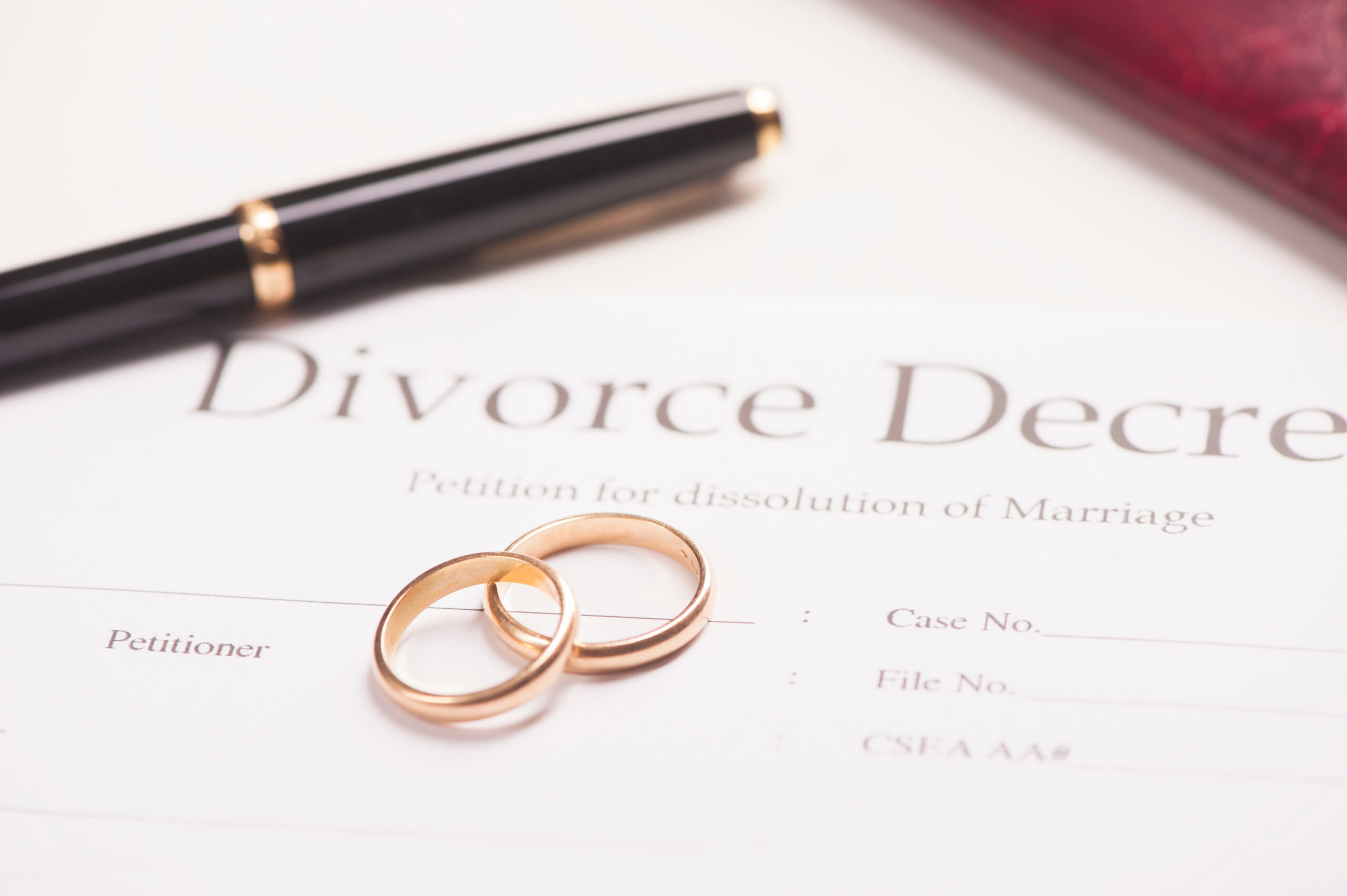divorce decree with wedding bands and a pen