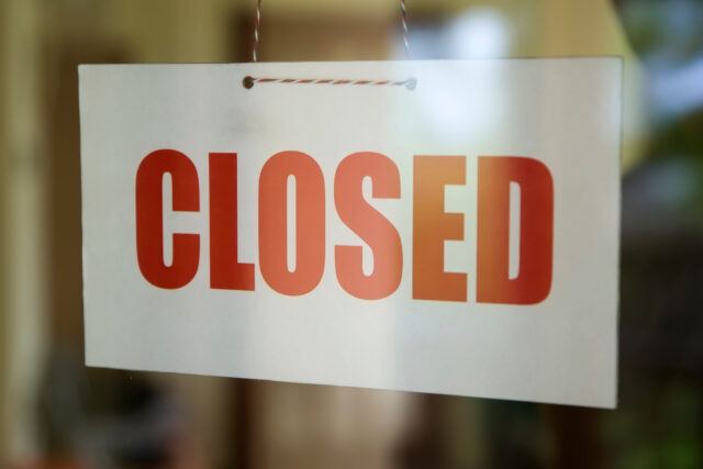 Closed sign board hanging on the glass door of cafe or small store